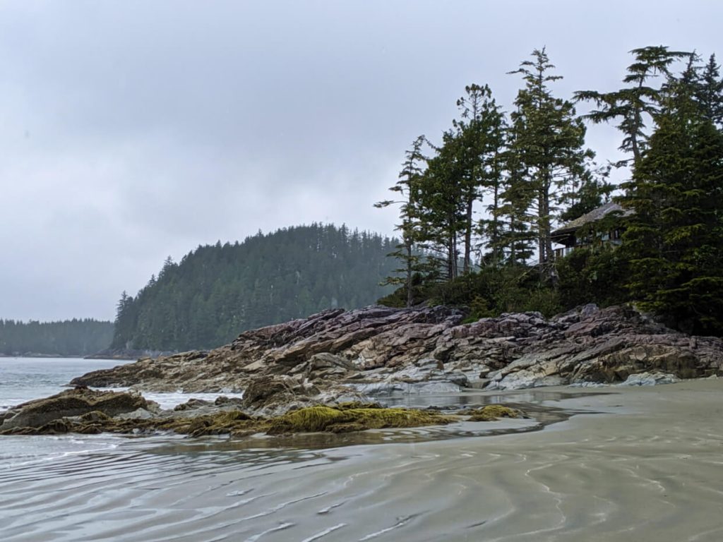 Rocky headland with trees, on sandy beach in Tofino